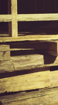In a warm, inviting workshop, rustic wooden pallets rest in neat stacks, bathed in soft sunlight that dances across their surfaces, creating a serene and industrious atmosphere.