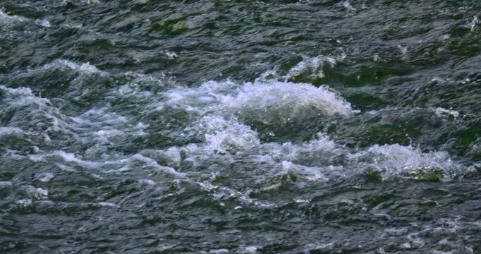 Close up of fast flowing river rapids with white foam and textured freshwater surface in slow motion Natural current movement ripples eddies and turbulent water create a dynamic abstract nature