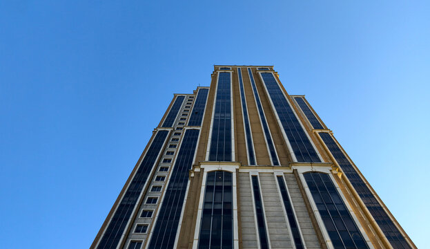 Tall building stands against clear blue sky in a busy urban area during daylight hours with no clouds in sight