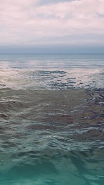 Gentle waves roll across the serene ocean surface, reflecting shades of pink and blue from the twilight sky. A peaceful atmosphere envelopes the tranquil scene, inviting calmness.