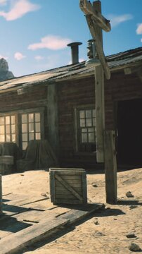 Sunlight bathes a charming wooden cabin in a desert setting. Storage crates sit on the ground, hinting at a story of past journeys and adventures in this tranquil scene.