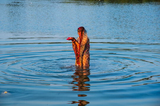 Traditionally dressed Indian woman pray into the river on Chhat Puja Festival.