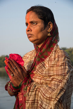 Traditionally dressed Indian woman pray into the river on Chhat Puja Festival.