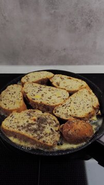 Delicious slices of eggy french toast frying in sizzling butter. A spatula flips the golden brown bread, revealing the perfectly cooked side