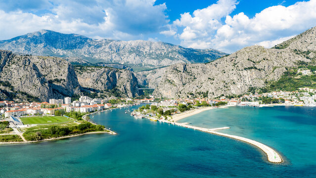 Aerial view of the historic town at the mouth of the Cetina river, surrounded by dramatic limestone cliffs and the turquoise Adriatic Sea in Omis, Split-Dalmatia County, Croatia.