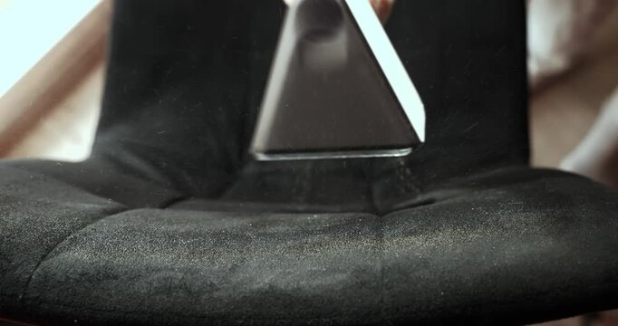 Vacuum cleaner refreshes a chair in a living room during home cleaning