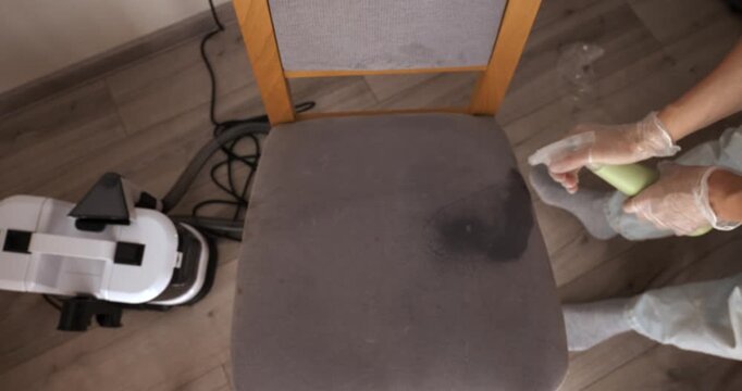 Cleaning a fabric chair with a wet vacuum and spray in a home interior