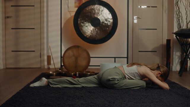 Woman lying in prone yoga stretch reaching forward on floor