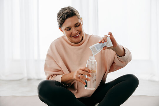 Hydration comes first as the woman mixes a supplement after workout at home