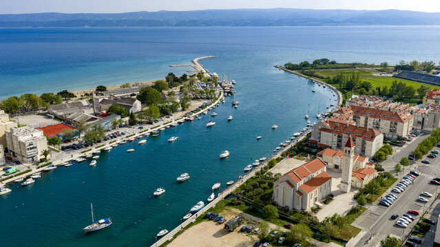 Aerial view of the Cetina river mouth with moored boats, the historic church of St. Peter, and the Adriatic Sea in Omis, Split-Dalmatia County, Croatia.