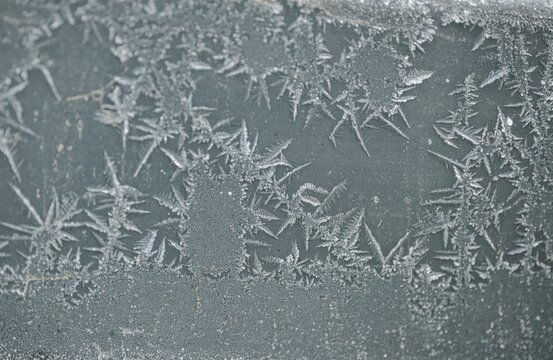 Frost crystals on frozen glass surface in winter close up
