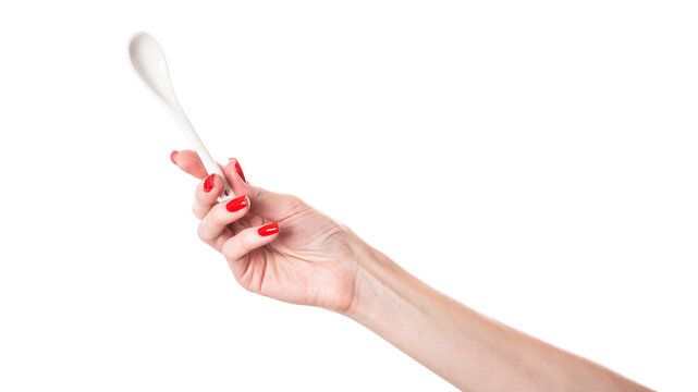 White ceramic tea spoon in female hand isolated on white background.