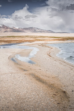 Mountain landscape, a cold high-altitude lake against the backdrop of rocky peaks and ridges with snow and glaciers, a panorama in the Tien Shan Mountains in the Pamirs, a lake with waves