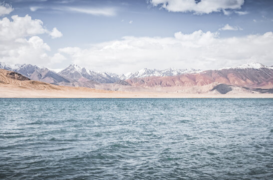 Mountain landscape, a cold high-altitude lake against the backdrop of rocky peaks and ridges with snow and glaciers, a panorama in the Tien Shan Mountains in the Pamirs, a lake with waves