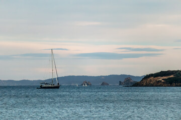 Fototapeta premium Sailboat on the Mediterranean Sea near Giens peninsula with rocky coastline and distant hills