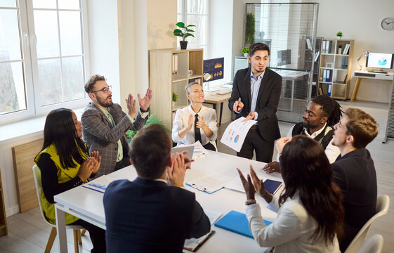 Business team meeting with presentation and applause. In a bright office, a leader presents a sales report with charts as colleagues applaud. Positive teamwork and success concept in business.