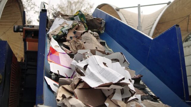 Paper and cardboard recycling. Waste paper and cardboard are loaded onto a pressing conveyor. Recycling of secondary raw materials. Industry and ecology. Paper and cardboard recycling.