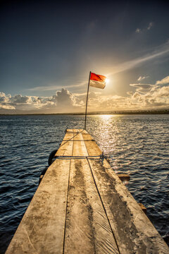 Indonesian flag on a flagpole at the end of a wooden pier, Tumbak Bentenan Marine Park, Southeast Minahasa, North Sulawesi, Indonesia