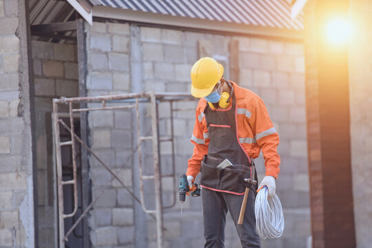 Male construction worker wearing a face mask standing on scaffolding at a construction site