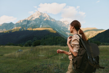 Naklejka premium Woman hiking with backpack in a grassy meadow before distant mountains, embracing nature and outdoor lifestyle, peaceful landscape and travel vibe