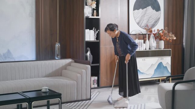 Senior elderly woman cleaning, sweeping with mop in hardwood floor. Elderly lady doing household chores and mopping the floor at home. Housekeeping and active retirement concept.