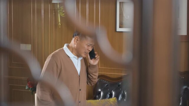Frustrated senior or old man having a heated conversation argument with someone while talking on mobile phone. He looks very angry and stressed out holding mobile device. Male suffer bad news.