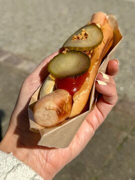 Close-up of a woman standing outdoors holding a traditional Danish hotdog