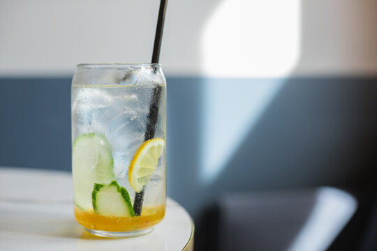 Close-up overhead view of a yuzu and melon drink with cucumber, lemon and ice in a tall glass on a table
