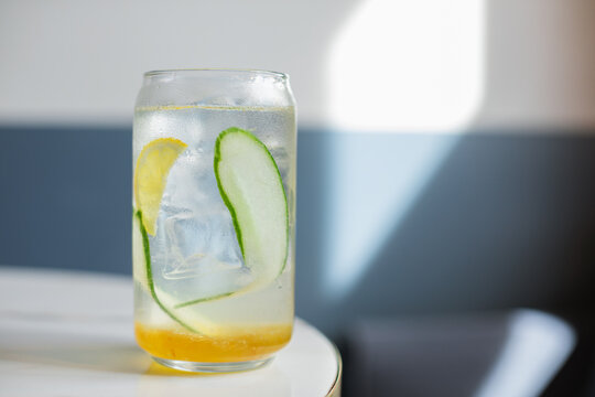 Close-up overhead view of a yuzu and melon drink with cucumber, lemon and ice in a tall glass on a table