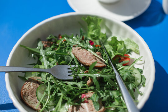 Close-up overhead view of a roast beef salad on a table at an outdoor cafe