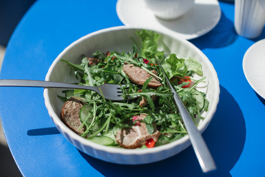 Close-up overhead view of a roast beef salad on a table at an outdoor cafe