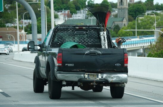 Wilmington, Delaware, U.S.A - May 2, 2026 - A black Ford F-250 carrying landscaping tools, including rakes and hose reel, driving on multi-lane road.
