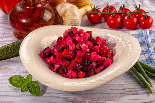Traditional Russian vinaigrette salad with beetroot and fresh vegetable ingredients on wooden table