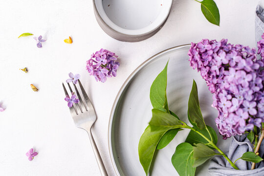 Close-up overhead view of a rustic spring place setting on a table with fresh lilac flowers