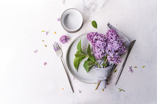 Close-up overhead view of a rustic spring place setting on a table with fresh lilac flowers