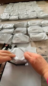 Moscow, Russia, 03.05.2026 Woman packing small cable product for online order. Seller preparing parcel for shipping. Home business logistics, supply chain management, delivery preparation.