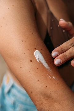 Woman applying sunscreen on arm for sun protection