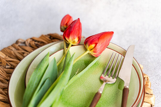 Overhead view of a rustic Spring place setting on a table with red tulips