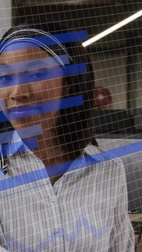 Vertical video: Woman at office glass with blue bars turning to camera after off-frame cue, smiling