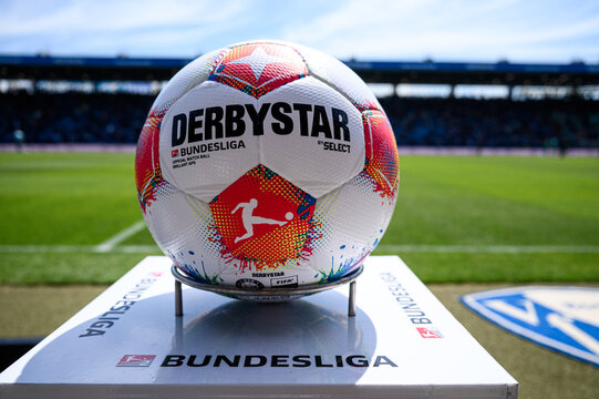 Official match ball on Bundesliga plinth at a football stadium before kickoff, close-up sports equipment with blurred stands in background.