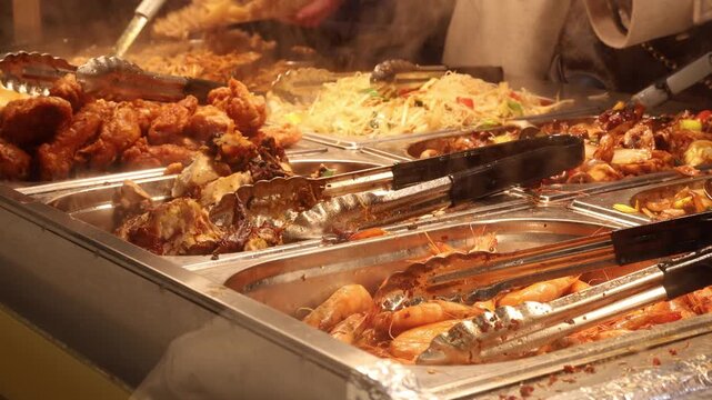 People putting food on plates in self service Chinese buffet restaurant