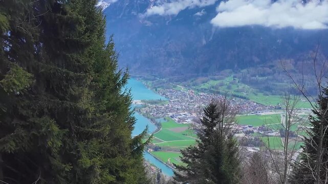 Scenic elevated view above Interlaken, Switzerland from the Harder Kulm funicular route featuring turquoise rivers, alpine valleys, forests, and mountain scenery.