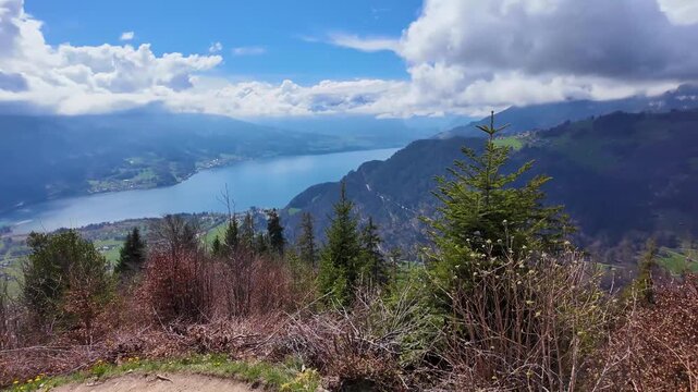 Stunning panoramic view from Harder Kulm above Interlaken, Switzerland featuring Lake Brienz, alpine valleys, forests, and dramatic mountain clouds.