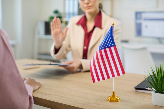 Immigration consultant interview shows visa rejection. In the office a client presents documents and application as the adviser raises a refusal hand. Clear concept of immigration rejection.