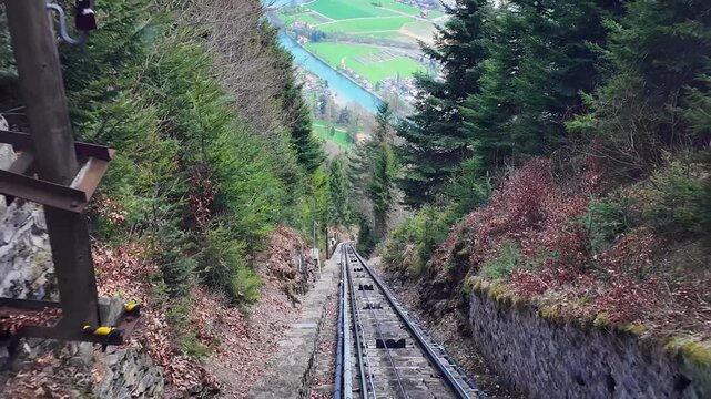 Scenic travel shot from the funicular ascending toward Harder Kulm above Interlaken, Switzerland with mountain views, forests, and alpine surroundings.