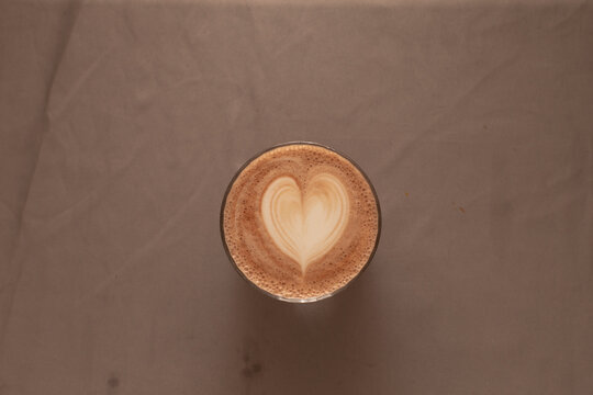Overhead perfect heart latte symmetry, centered composition, smooth microfoam, muted backdrop, craft coffee presentation, calm morning ritual, balanced aesthetic