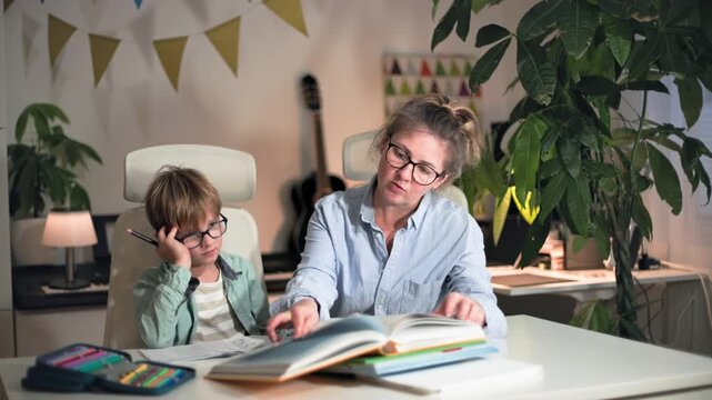 A young woman, checking her son homework, encourages him and kisses him