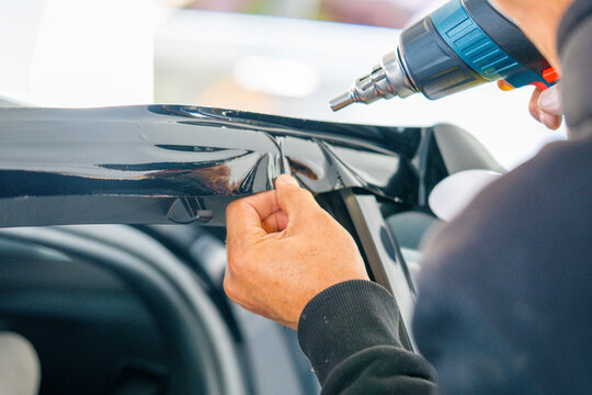 A car wrapping specialist applies a polyurethane film to the car. Detailer PPF