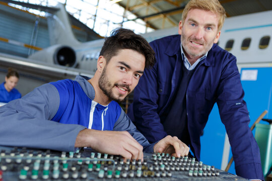 young male technician adjusting dismantled aviation control panel