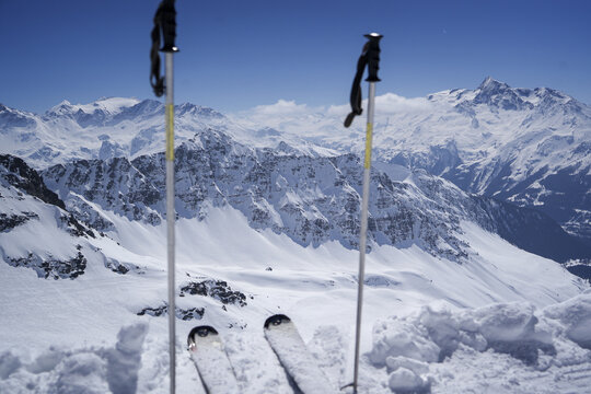 Aerial view of the snow-covered Alpine peaks at La Rosiere ski resort with ski tips and poles in the foreground under a clear blue sky in Montvalezan, Auvergne-Rhone-Alpes, France.